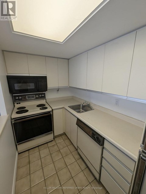 A kitchen with white cabinets and a black microwave.