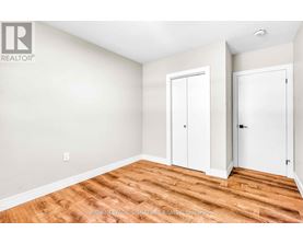 A room with wooden flooring and white walls with two doors.