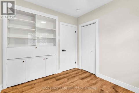 A white cabinet with glass doors is in a room with a wooden floor.