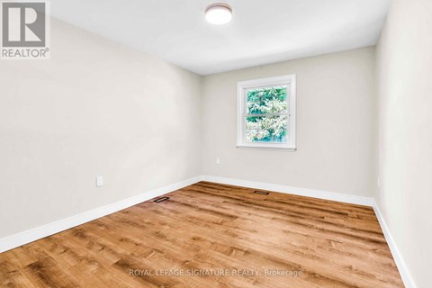 A room with wooden flooring and a framed picture on the wall.