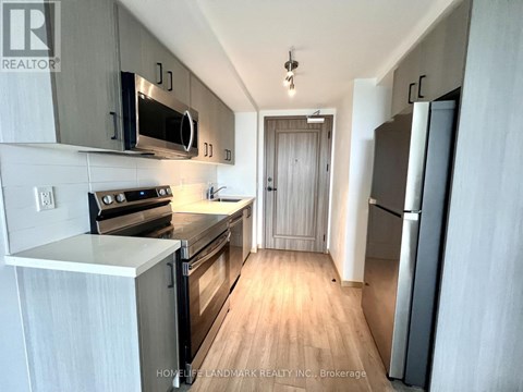 A modern kitchen with wooden floors and stainless steel appliances.