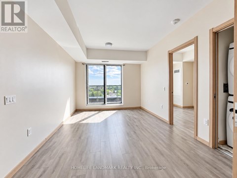 A spacious room with wooden flooring and a large window overlooking a balcony.