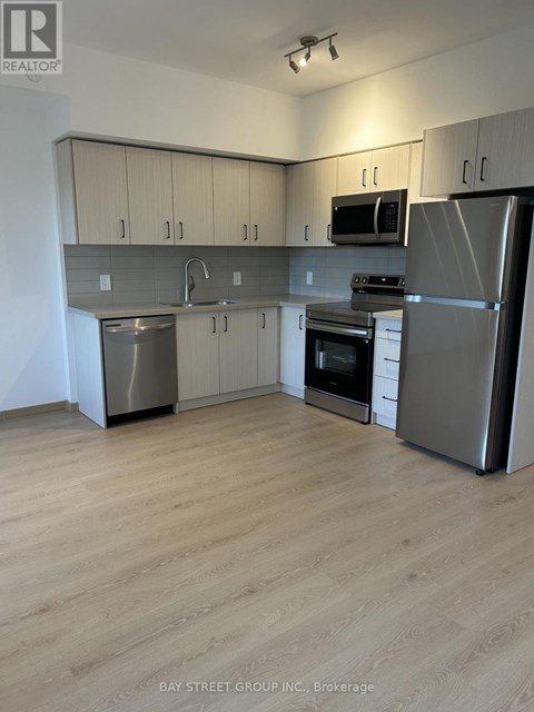 A kitchen with a refrigerator, oven, and microwave.