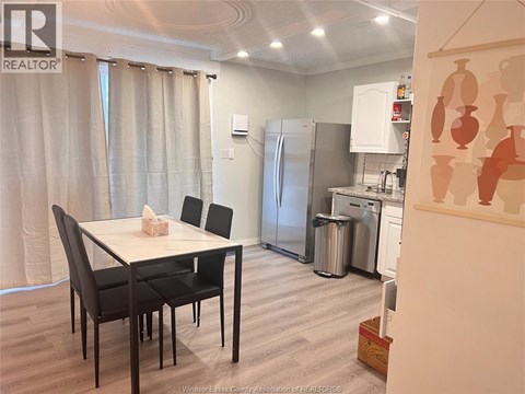A kitchen with a table and chairs in the foreground and a refrigerator in the background.