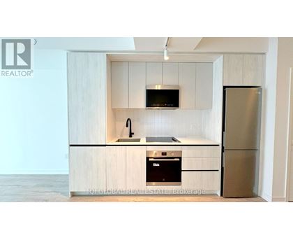 A kitchen with a refrigerator, microwave, and oven.