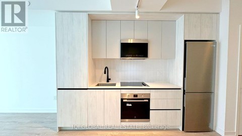 A kitchen with a refrigerator, microwave, and oven.