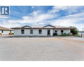 A white building with a brown roof and a sign that says REALTOR.