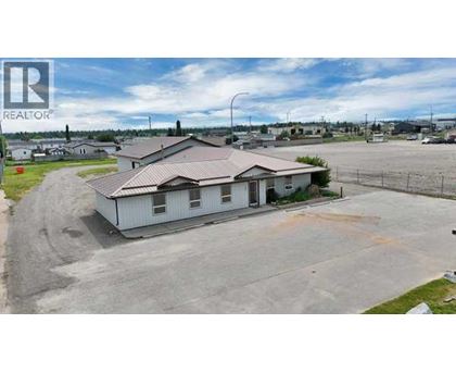 A house with a brown roof is surrounded by a parking lot.