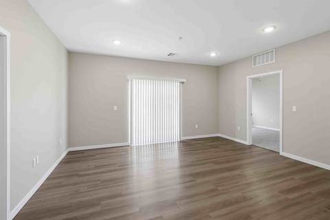 A spacious room with wooden flooring and white walls.