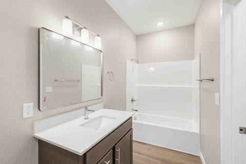 A white sink is on a brown vanity in a white bathroom.