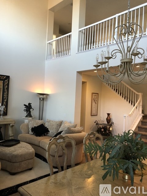 A living room with a couch, chairs, and a table with a plant on it.