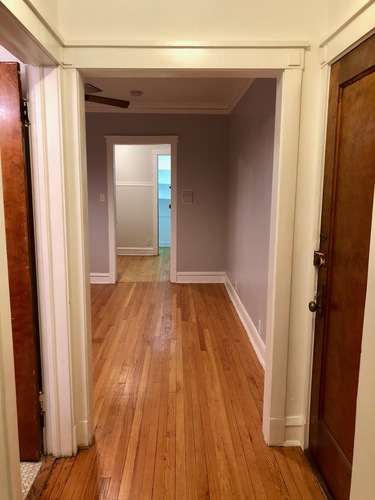 A hallway with wood floors and white walls.