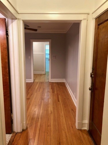 A hallway with wood floors and white walls.