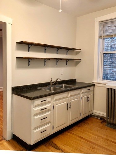 A kitchen with white cabinets and a black countertop.