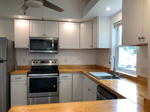 A kitchen with white cabinets and a wooden countertop.