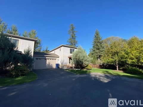 A house with a driveway and trees in the background.