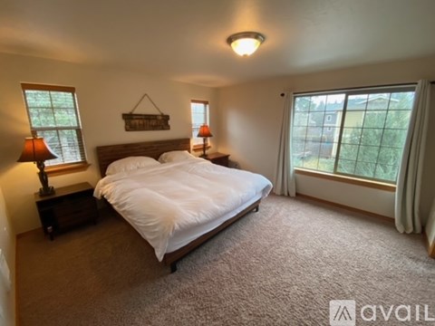 A bedroom with a large bed, two lamps, and a window.