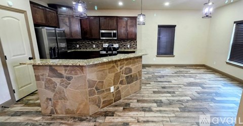 A kitchen with a stone counter top and wooden cabinets.