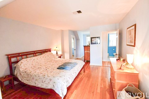 A bedroom with a large bed and wooden floors.