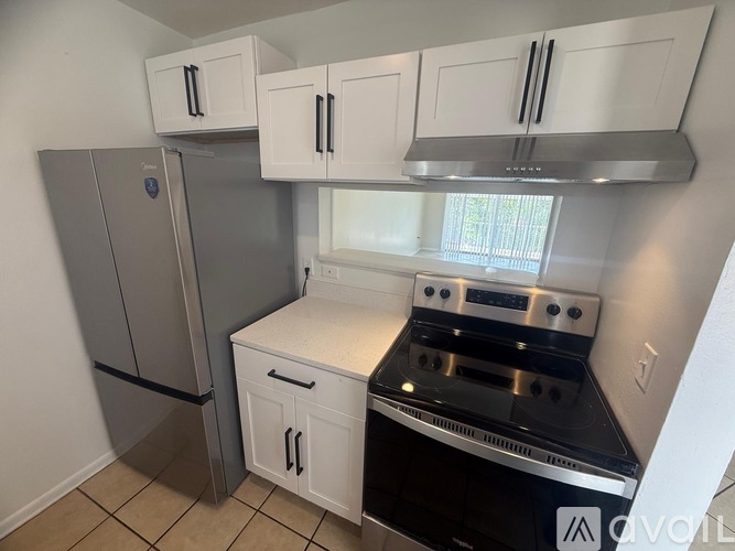 A kitchen with white cabinets and a stainless steel refrigerator.