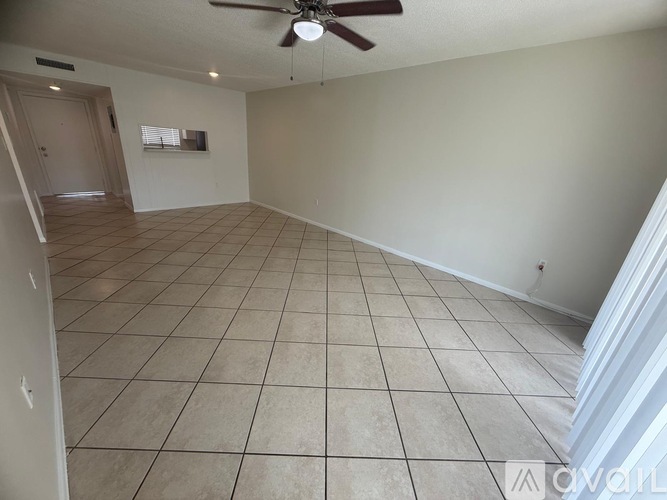 A spacious room with a ceiling fan and tiled flooring.