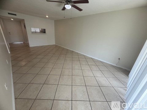A spacious room with a ceiling fan and tiled flooring.