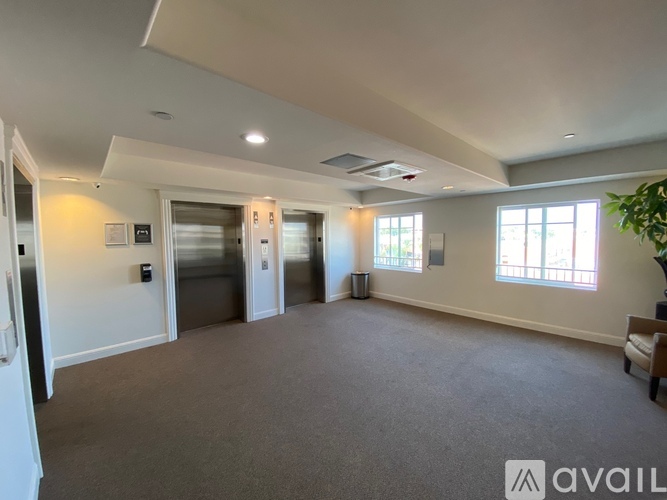 A spacious room with a carpeted floor, a ceiling fan, and a large window on the right wall.