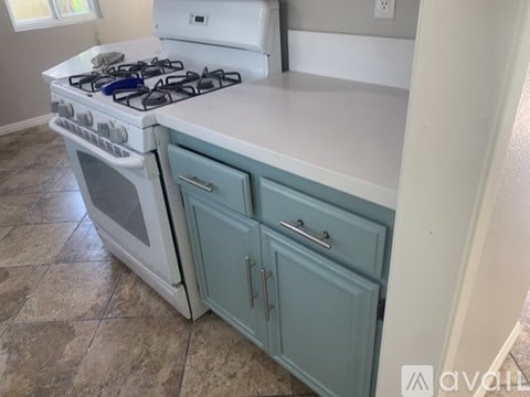 A white and blue kitchen with a white stove and blue cabinets.