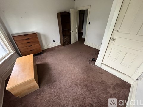 A room with a brown carpet and a wooden bench.