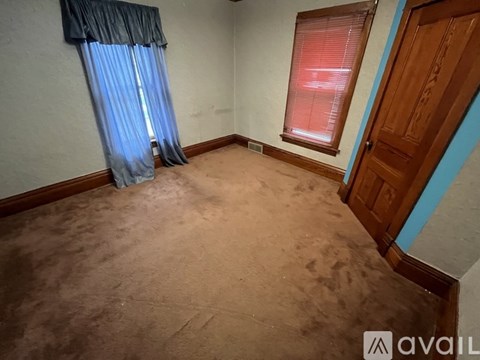 A room with a brown carpet and a blue curtain.