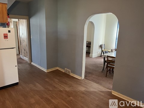 A kitchen with a white fridge and wooden floors.