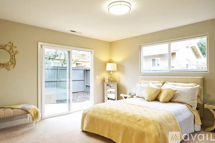 A bedroom with a bed, nightstand, and sliding glass doors.