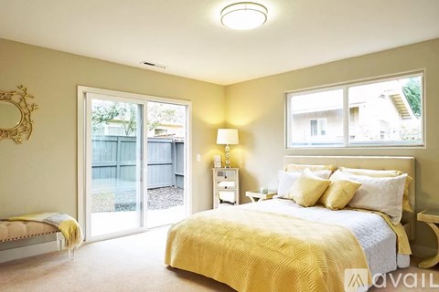 A bedroom with a bed, nightstand, and sliding glass doors.