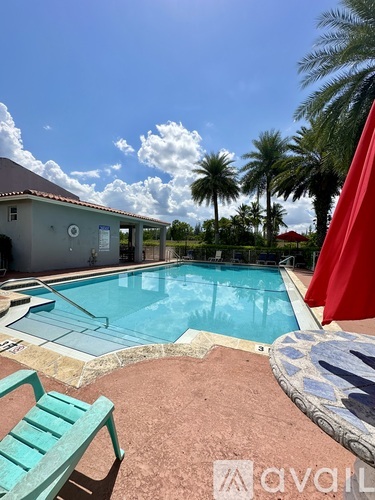 A pool with a red umbrella and a green bench.