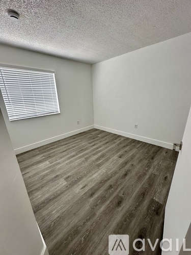 A room with wooden flooring and a window with blinds.