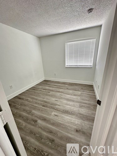 A room with wooden flooring and a window with blinds.