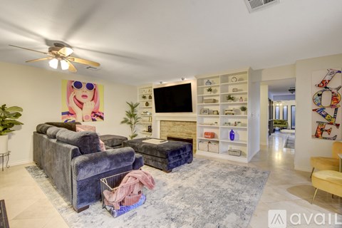 A living room with a grey sofa and a TV on a white wall.