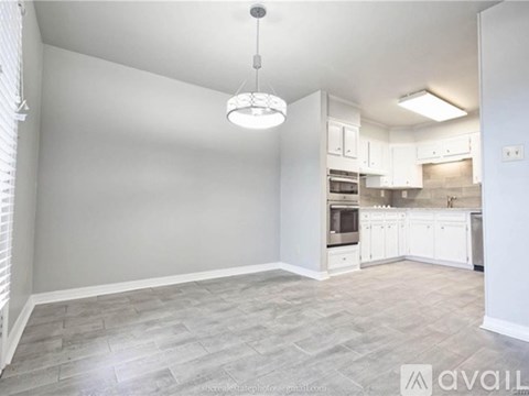 A spacious kitchen with white cabinets and a grey floor.