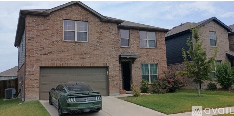 A green car is parked in front of a brick house.
