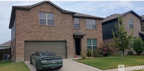 A green car is parked in front of a brick house.