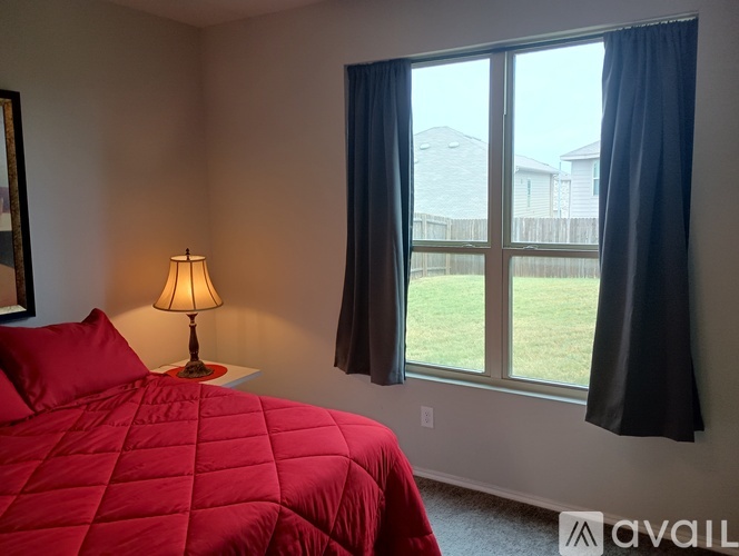 A bedroom with a red bedspread and a lamp on a bedside table.