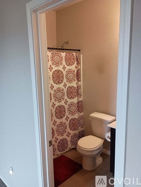 A small bathroom with a toilet and a shower curtain.