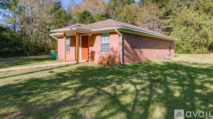 A house with a brown brick exterior and a green lawn in front.