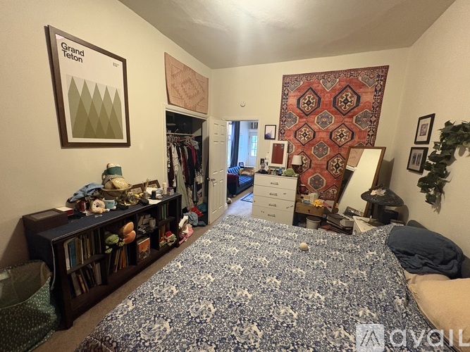 A bedroom with a large bed and a bookshelf filled with books and other items.