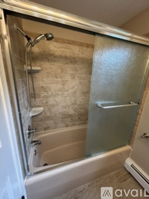 A bathroom with a glass shower door and a bathtub.
