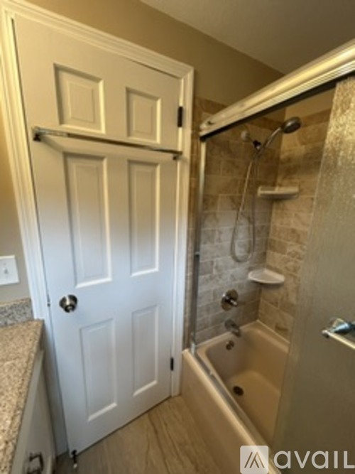 A white door is open to a bathroom with a tub and shower.