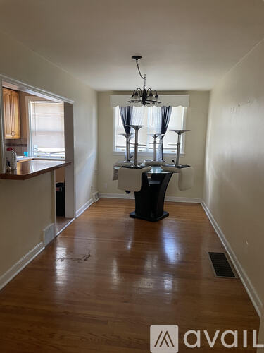 A long hallway with a chandelier and a trash can.