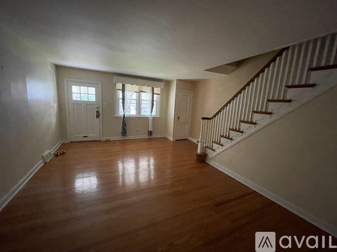A room with wooden floors and a staircase with white railings.