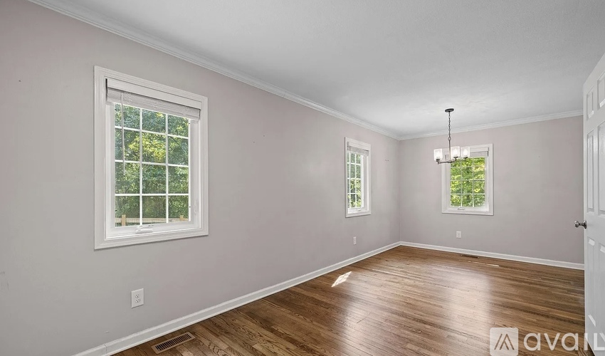 A room with wooden floors and two windows.