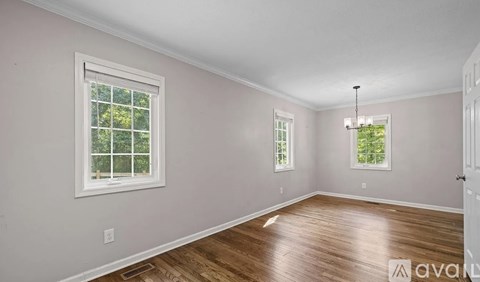 A room with wooden floors and two windows.